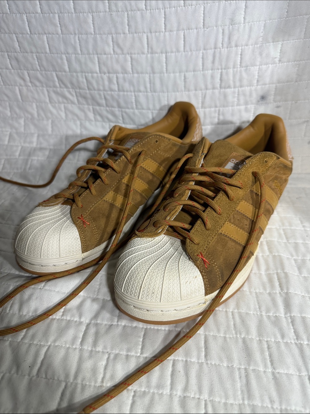 brown suede Adidas Superstar sneakers with a classic rubber shell toe